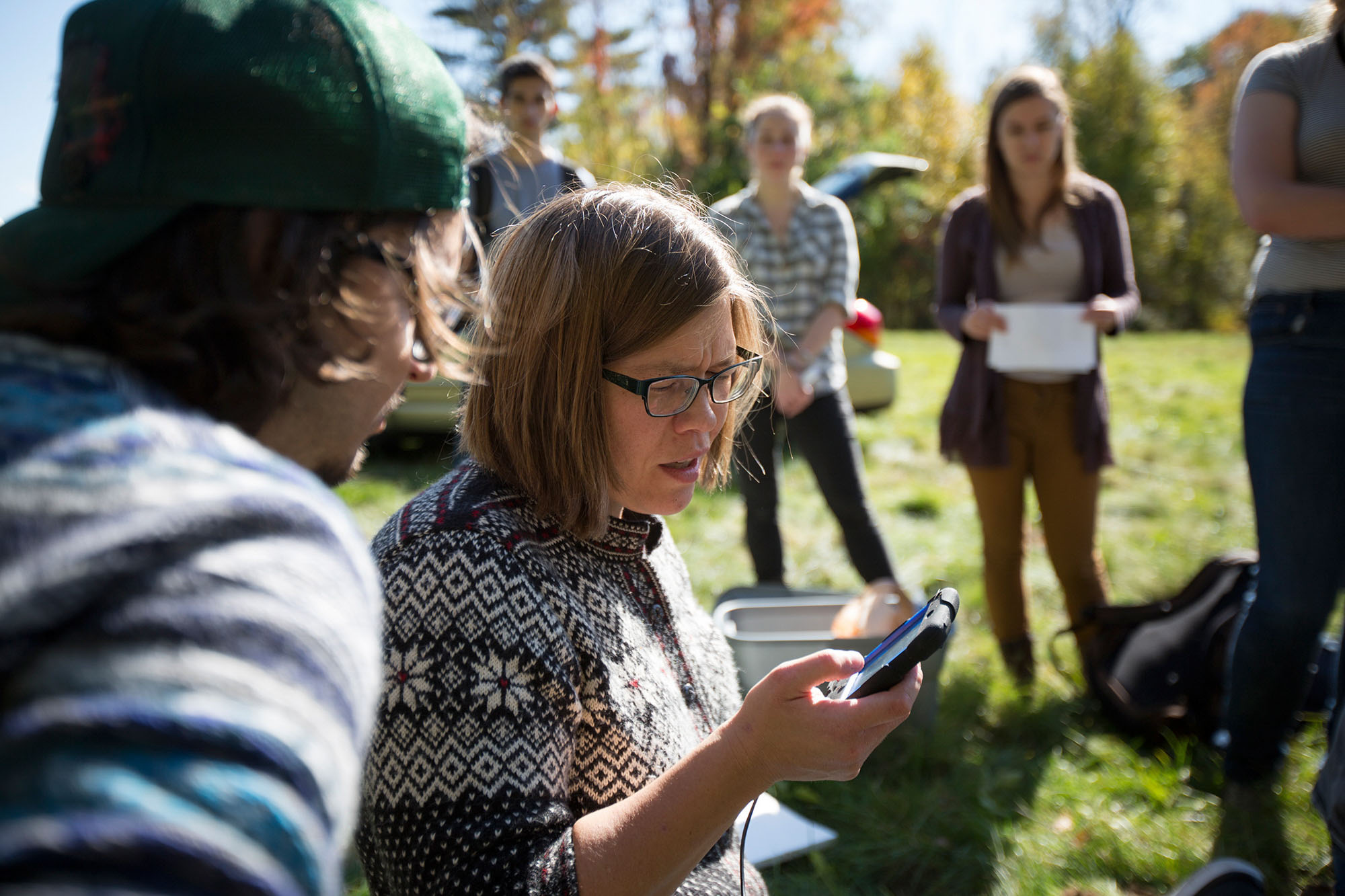 EAS Professor Kade Keranan stands outside and looks at a handheld piece of electronic equipment.