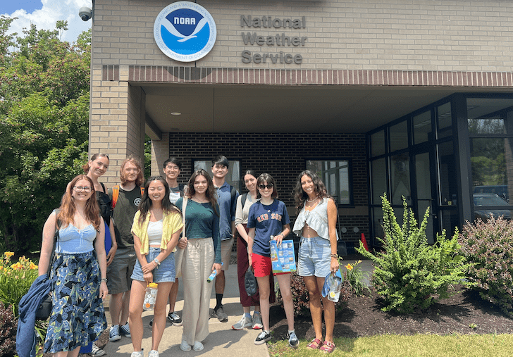 ten people stand outside the entrance to the Binghamton, New York office of the National Weather Service