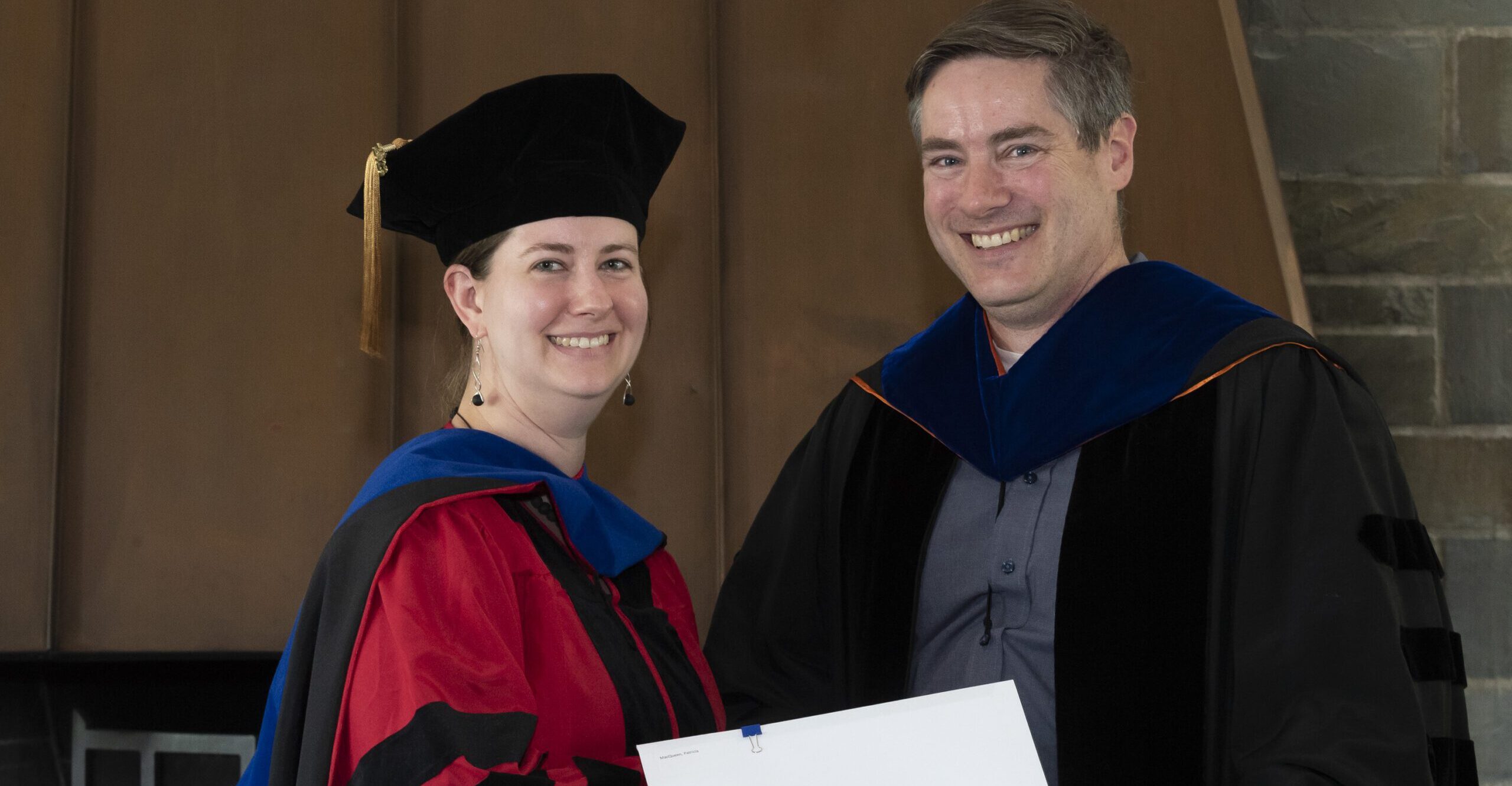 EAS Professor Matt Pritchard and a graduating Ph.D. student stand smiling and holding a diploma.