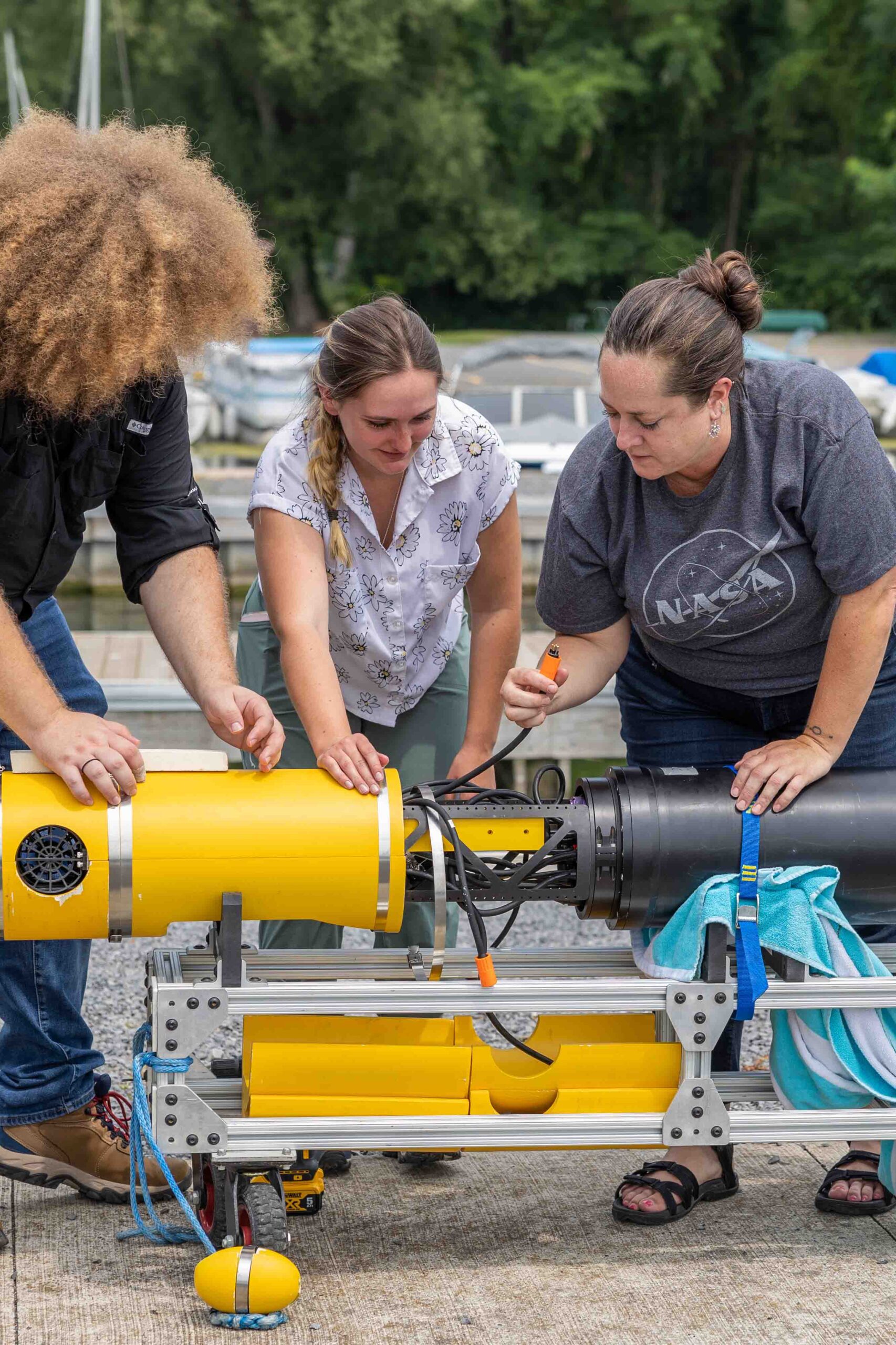 Britney Schmidt works with two students in front of the Icefin Robot at Cayuga lake