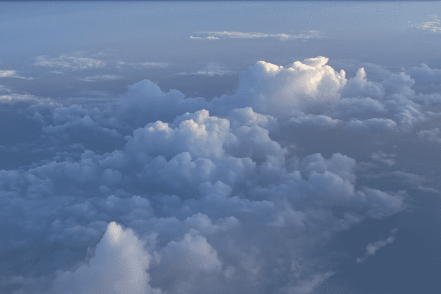 Cumulus clouds seen from above with their tops glowing white in sunlight.
