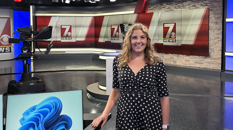 Nicole Collins standing and posing for a photo on the set of the television station where she works as a meteorologist.