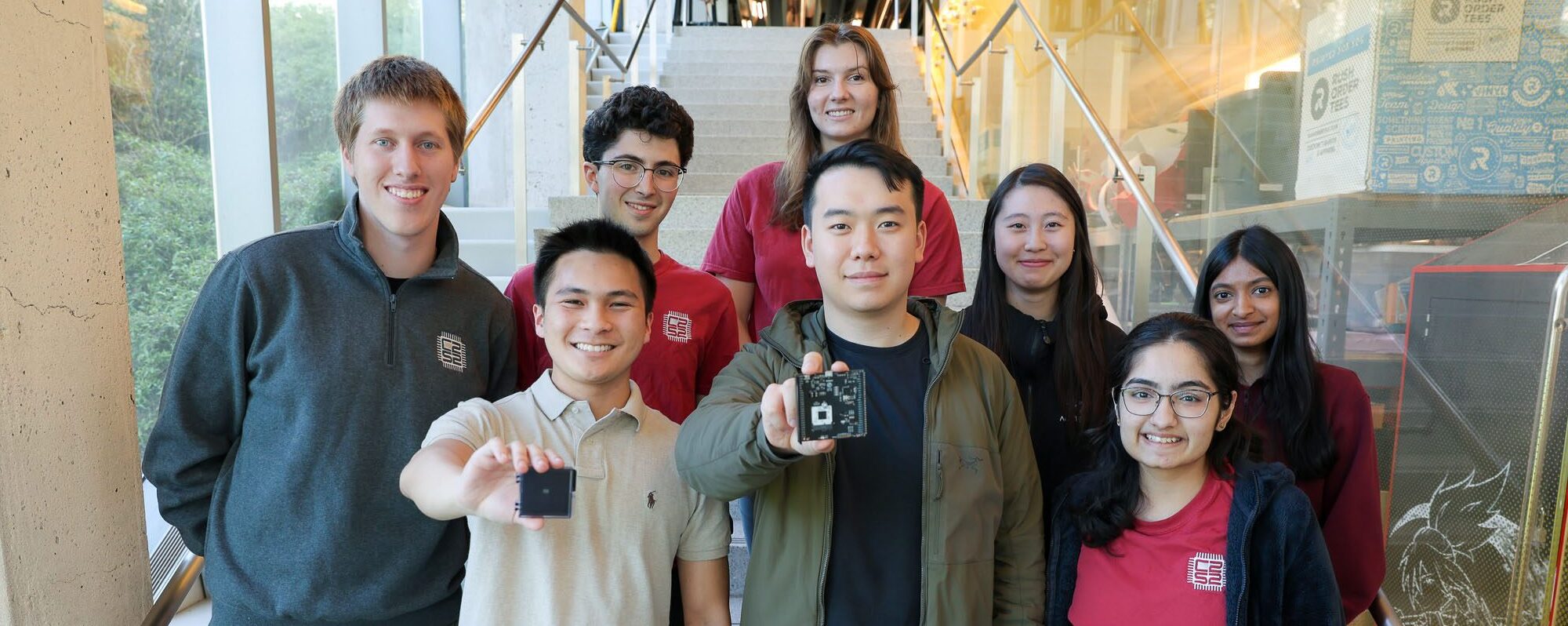 Group photo members of the C2S2 lab with 2 students holding up microchips and 6 other students standing around them smiling at camera