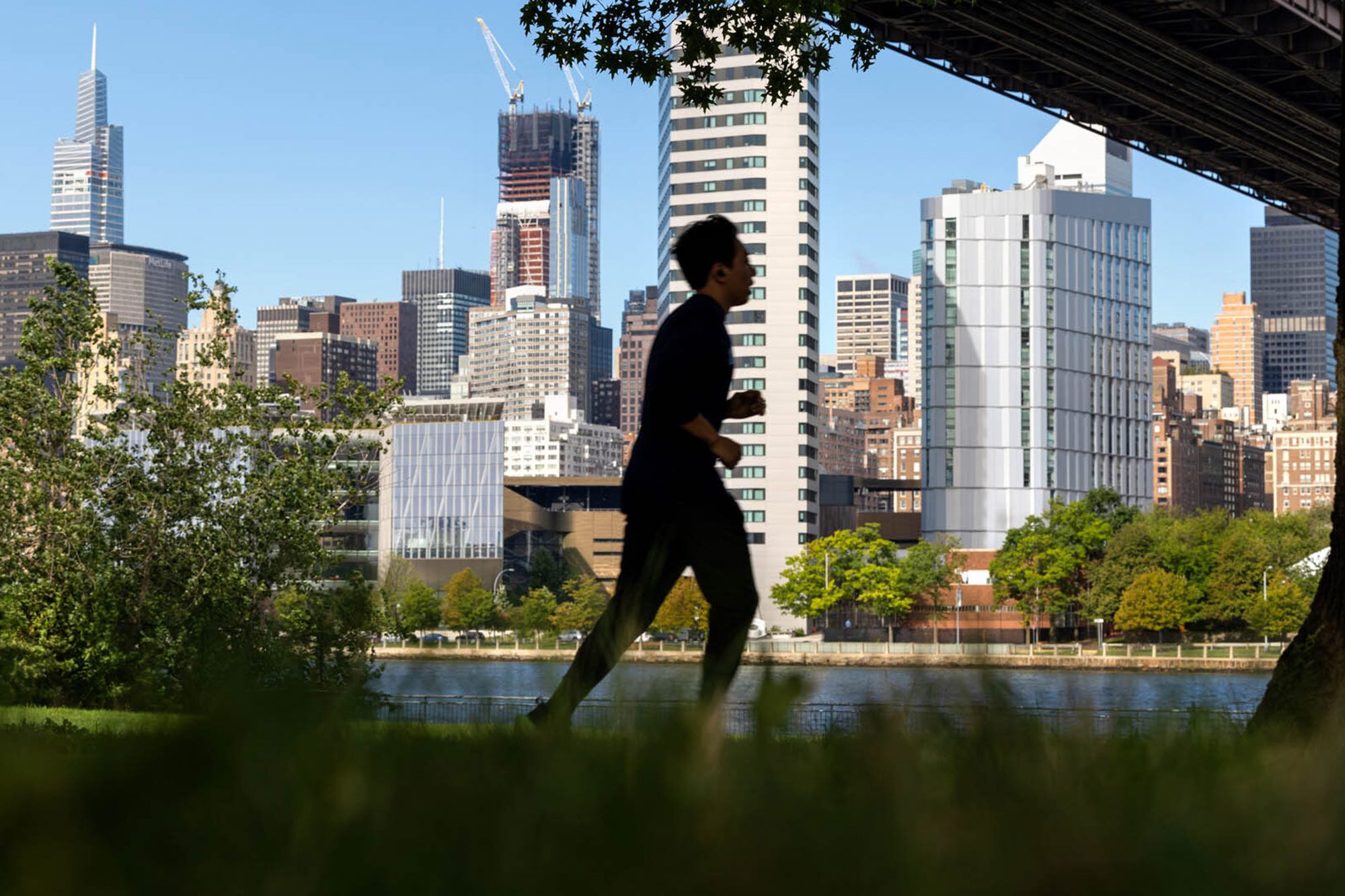 Sillouhette of a Cornell Tech student running in New York City with the city skyline behind them.