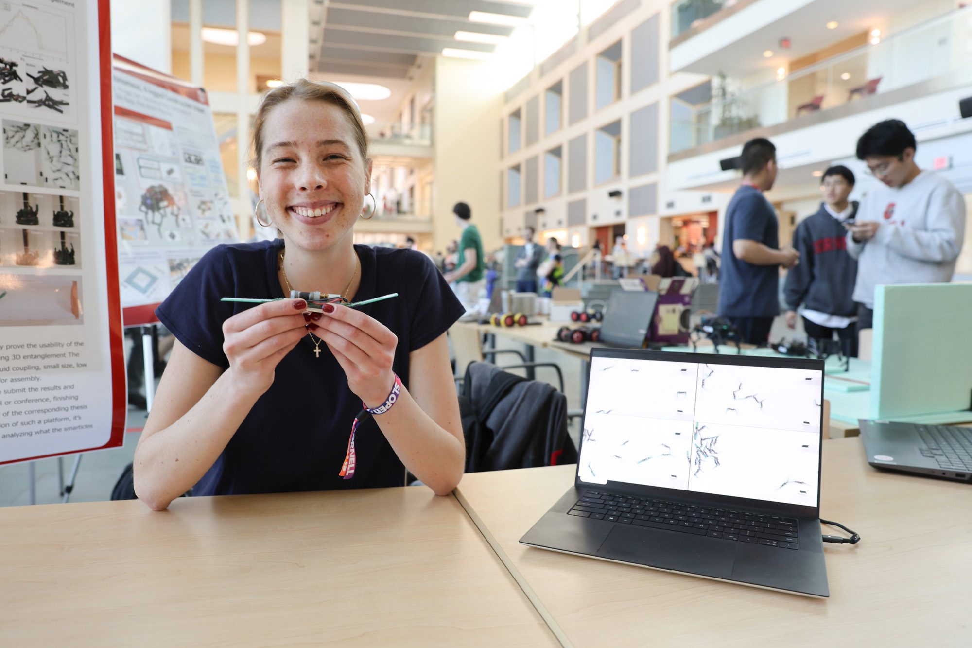 A student smiles and shows off a small robot
