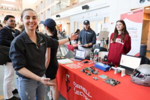 A student shows off the Cornell Electric Vehicles table at a robotics showcase