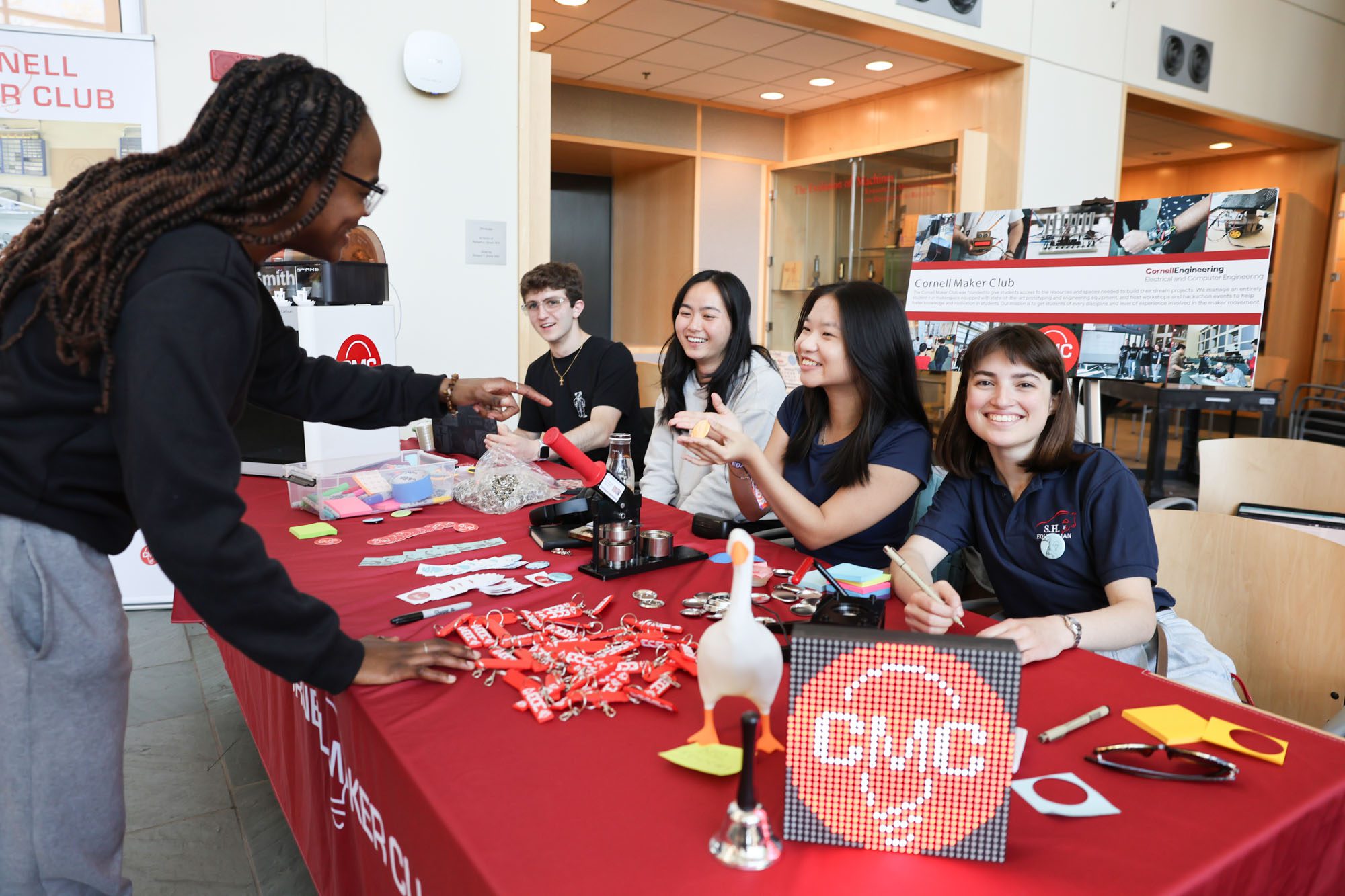 Students smile at the Cornell Maker Club table during a robotics showcase