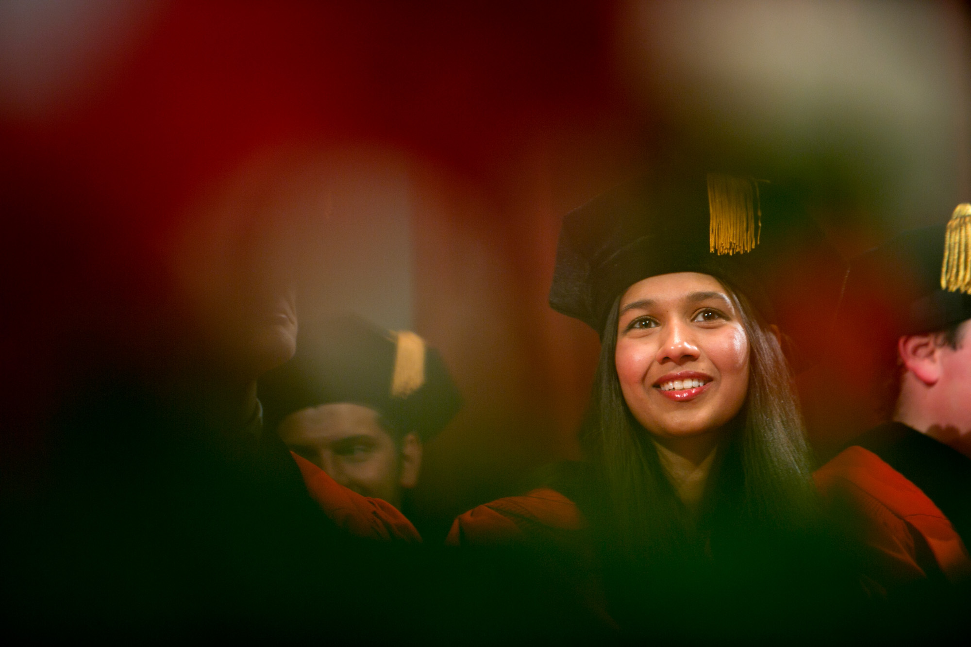 Student in a graduation cap and gown smiles.