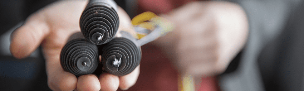 three black spiral robotic parts held in a hand