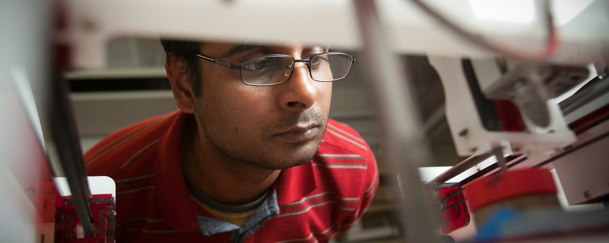 Apoorva Kiran watches as a 3D printer creates an audio speaker