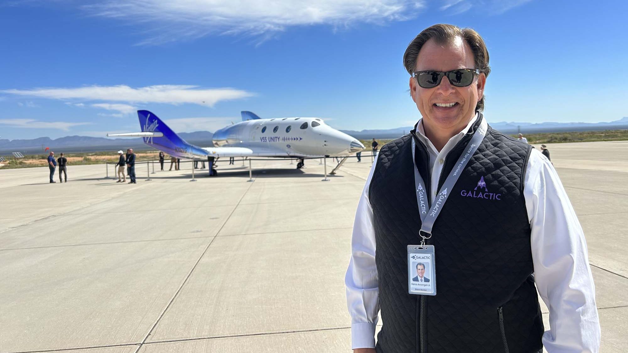 M.Eng. Alum Henio Arcangeli stands outside airport tarmac with Virgin Galactic aircraft behind him.