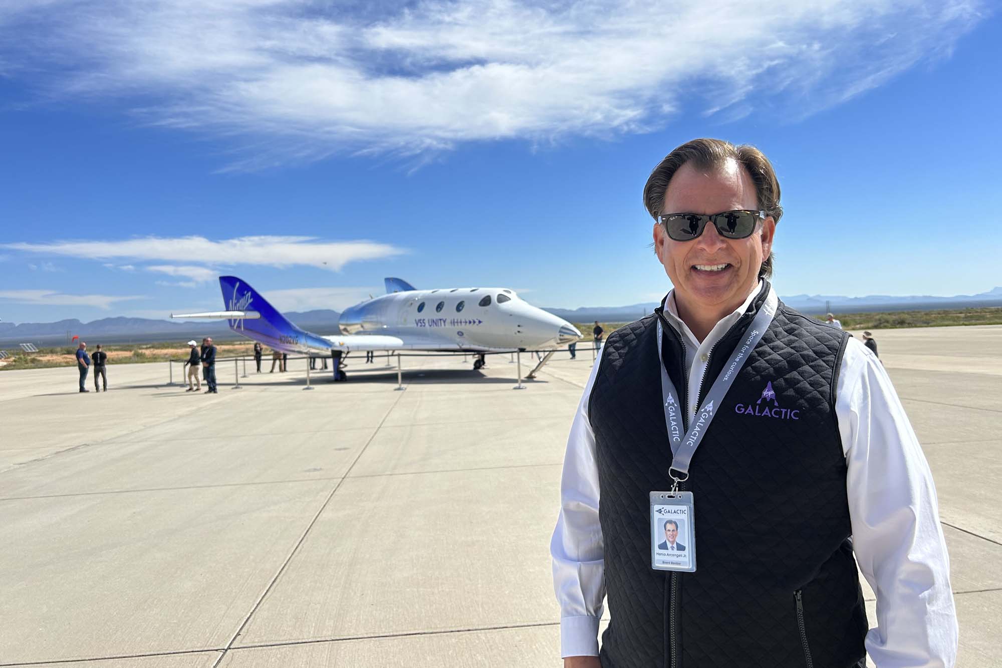 M.Eng. Alum Henio Arcangeli stands outside airport tarmac with Virgin Galactic aircraft behind him.