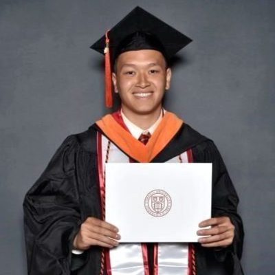 Student in graduation regalia smiling with a diploma