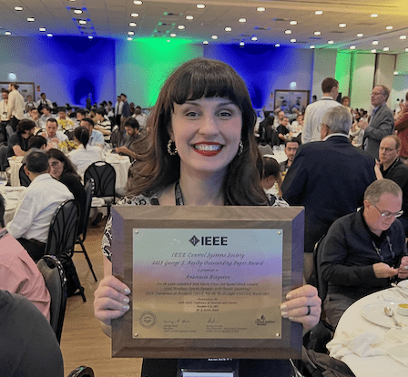 Anastasia Bizyaeva smiles while holding her Axelby Award plaque from IEEE.