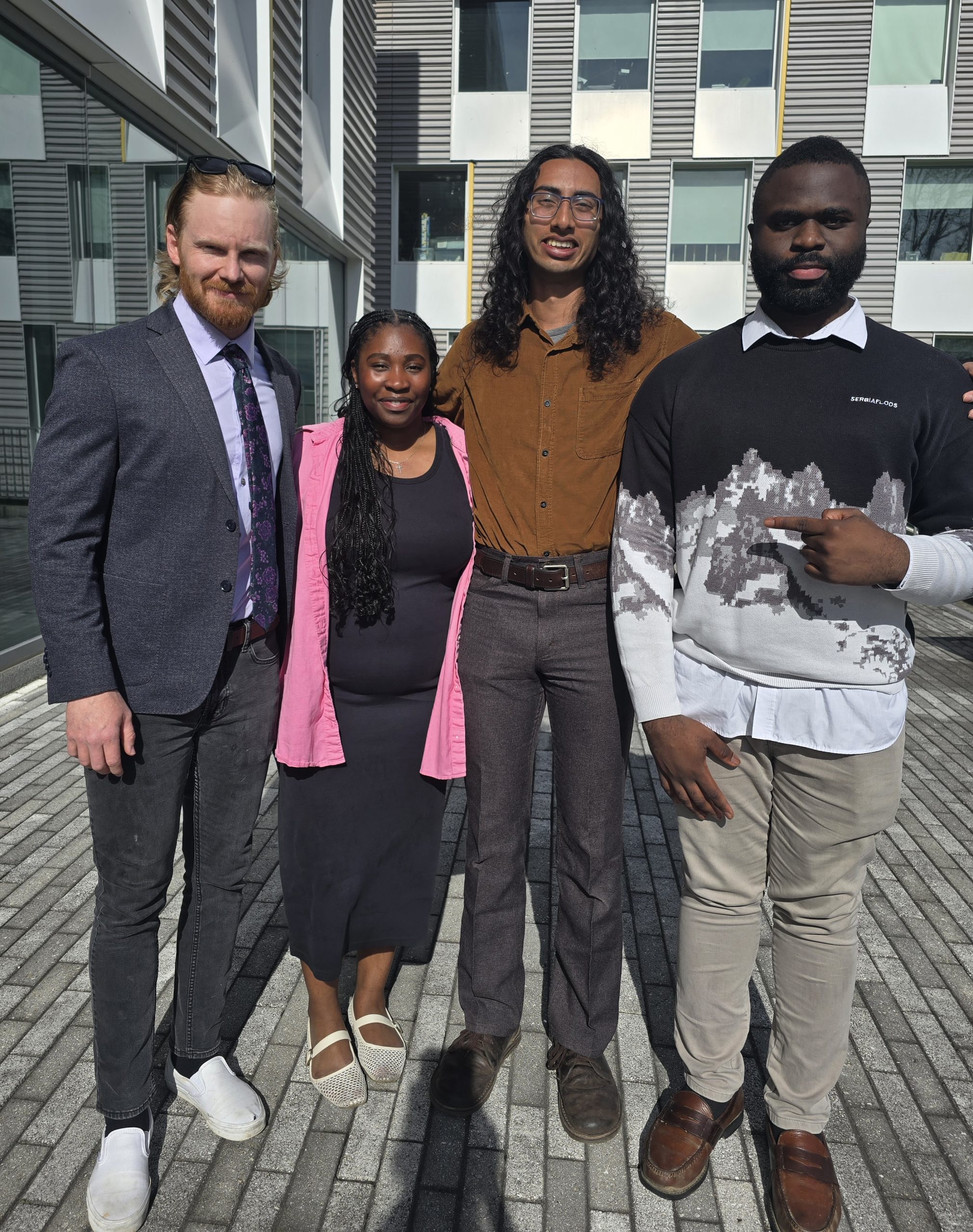 Four members of the Sibley Research Graduate symposium Planning Committee pose together outside of Upson Hall.