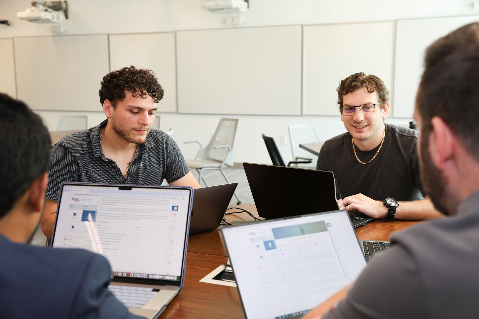Distance learning students sitting around a table working on their laptops during their residential experience