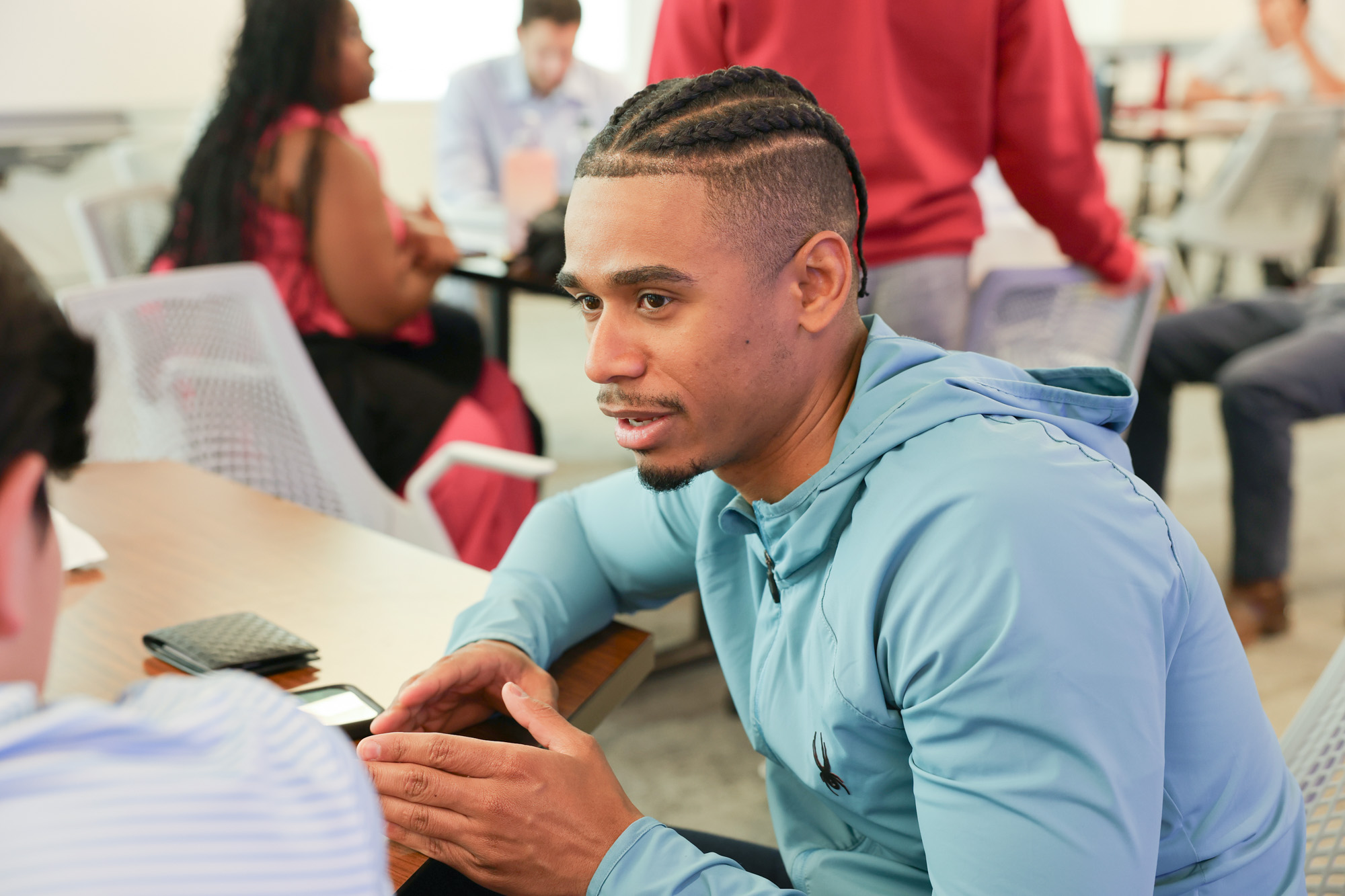 Distance learning students sitting around a table talking during their residential experience