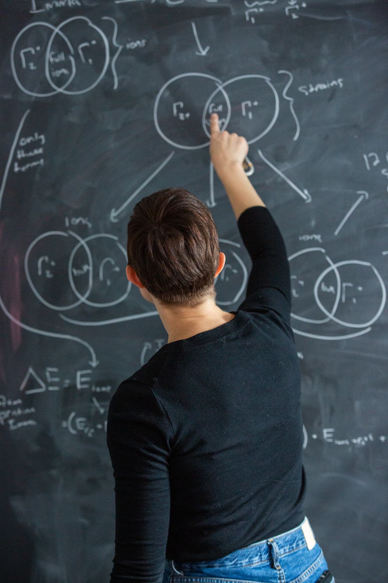 Associate professor Nicole Benedek writing a chemical equation on a chalk board