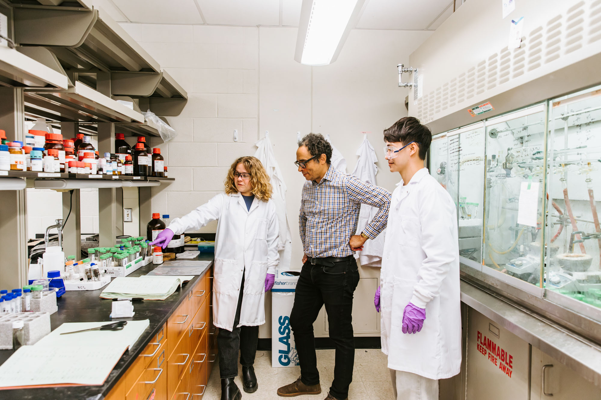 Two students talking with associate professor Richard Robinson in his research lab