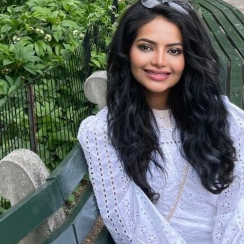 Female student sitting on a bench outside smilling