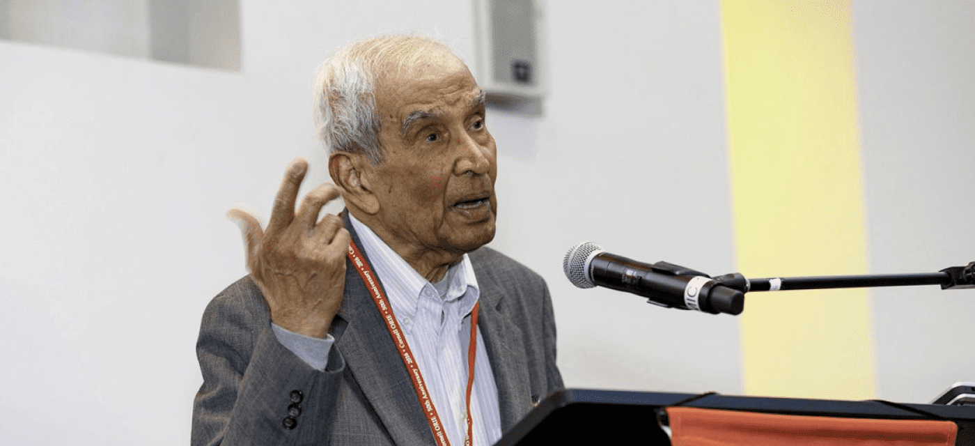 Uma Prabhu speaking at a microphone.