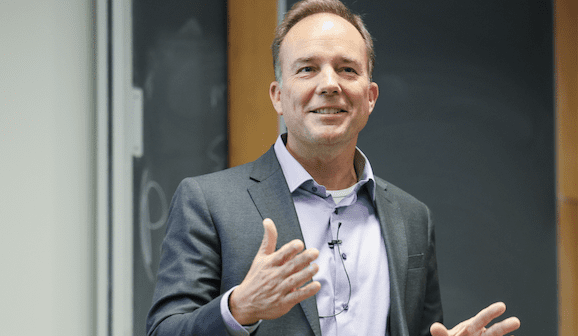 Jason Erdell gesticulates while delivering the 2025 Cheng L.ecture