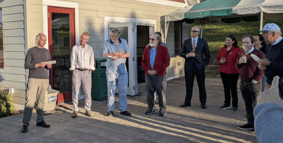 Jim Renegar and nine past and present Operations Research faculty members stand on the patio of Hopshire Brewery as Jim Renegar delivers remarks.