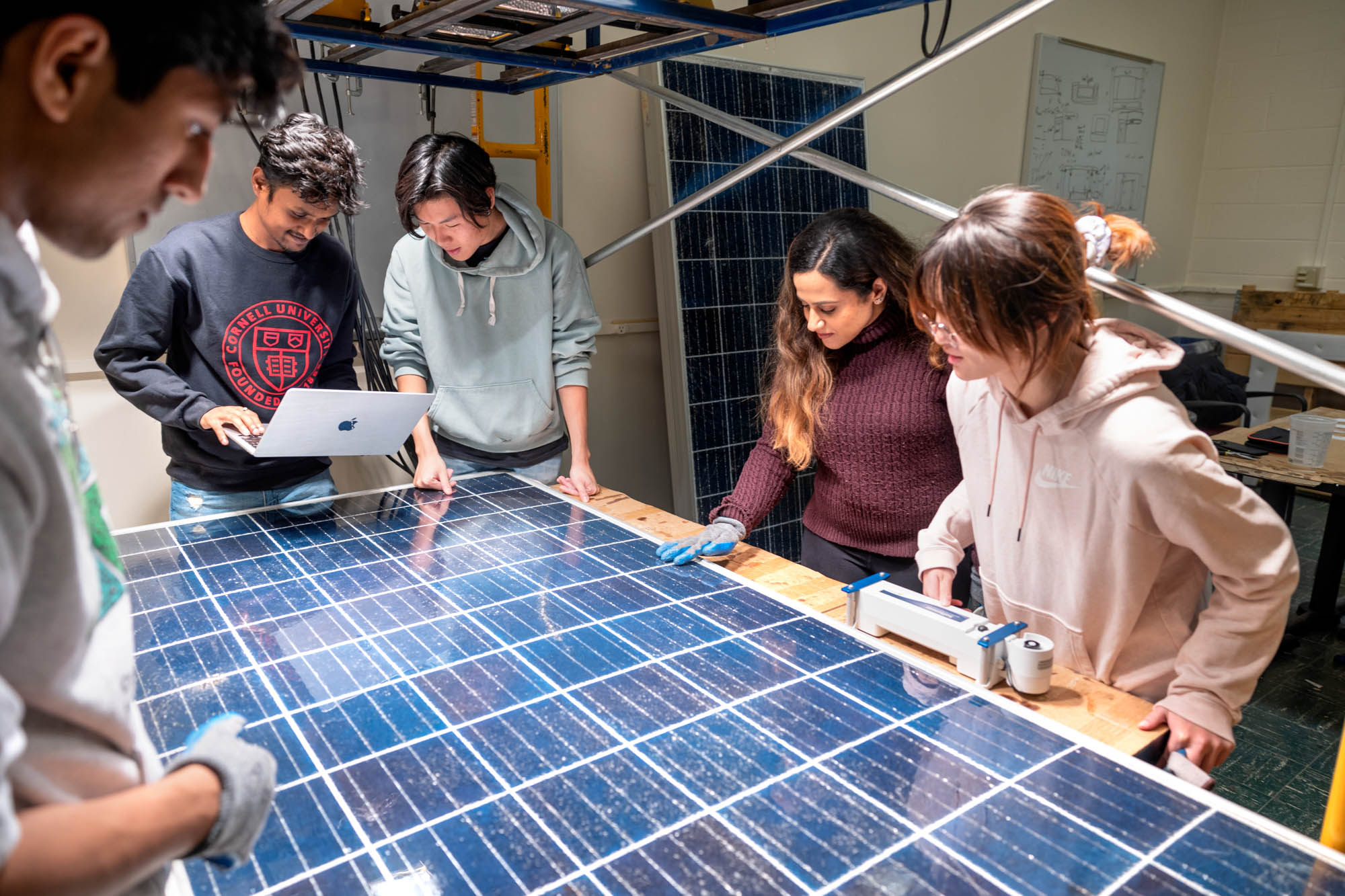 Students of the Cornell University Sustainable Design team work on their refurbished solar panels in Ward Laboratory