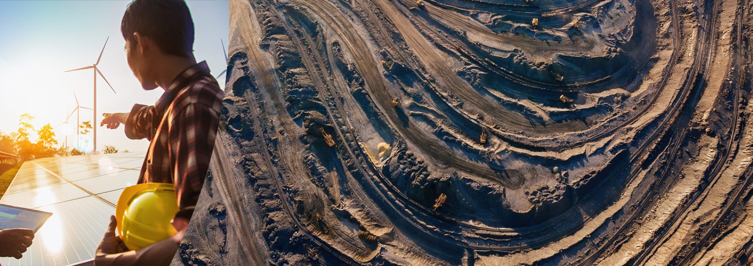 Scientist with hardhat points toward windmill at construction site with large swath of dirt roads