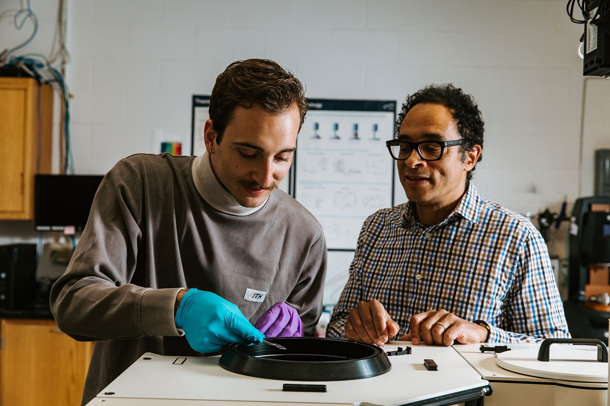 Researchers work together in lab using specialized equipment and wearing protective gloves