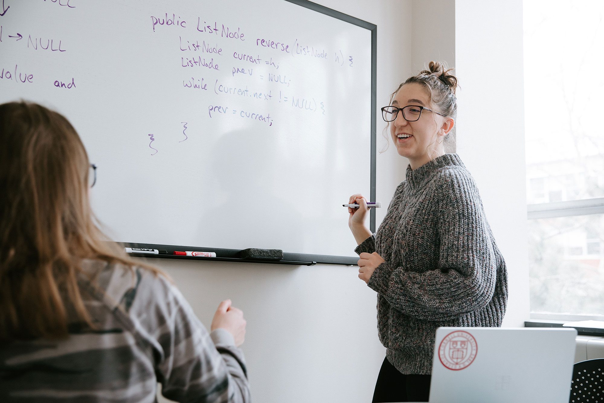 Career Center advisor works with student at whiteboard on coding interview