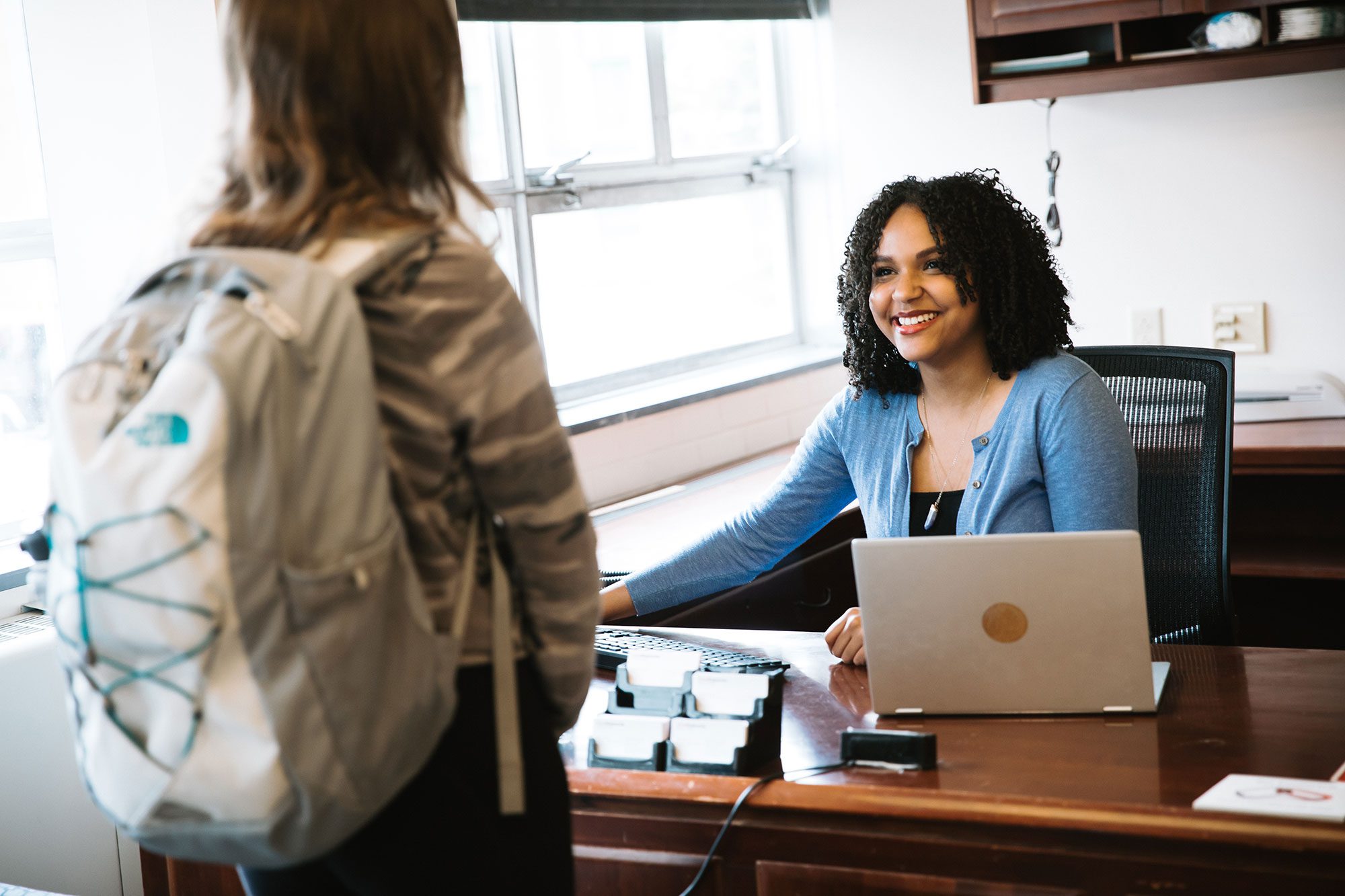 Career Center peer advisor at office desk greets student