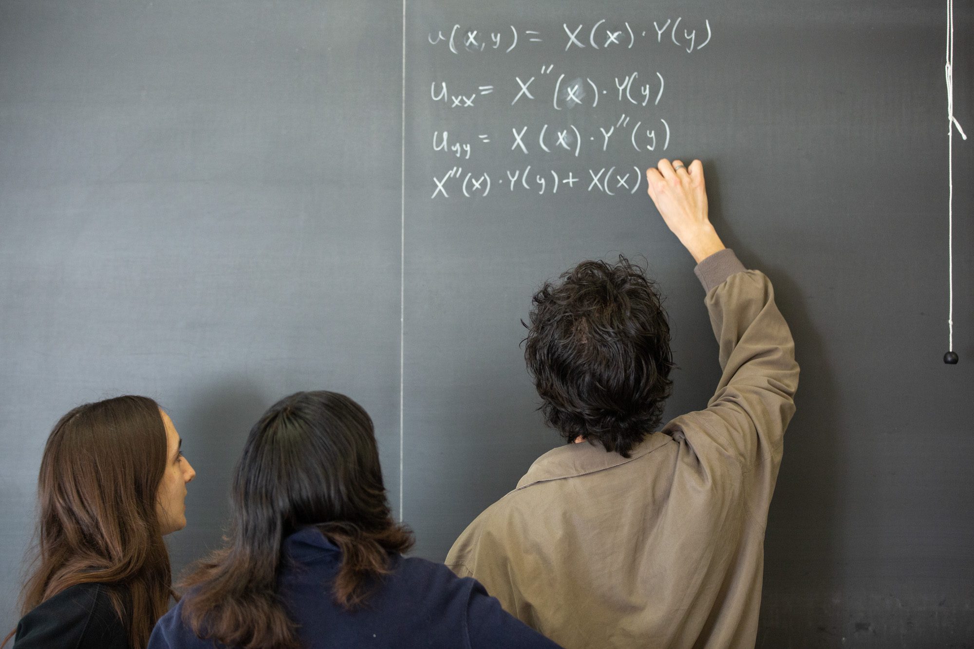 Students work together on equations at a chalkboard during an Academic Excellence Workshop