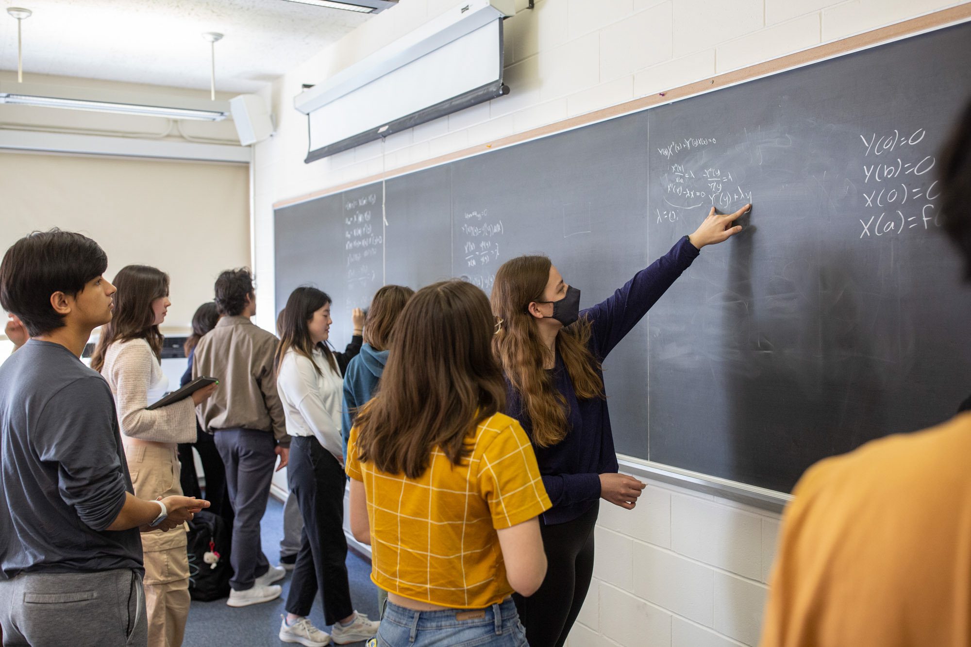 Students work together on equations at a chalkboard during an Academic Excellence Workshop