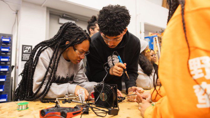 Two students work together with wires and electrical devices
