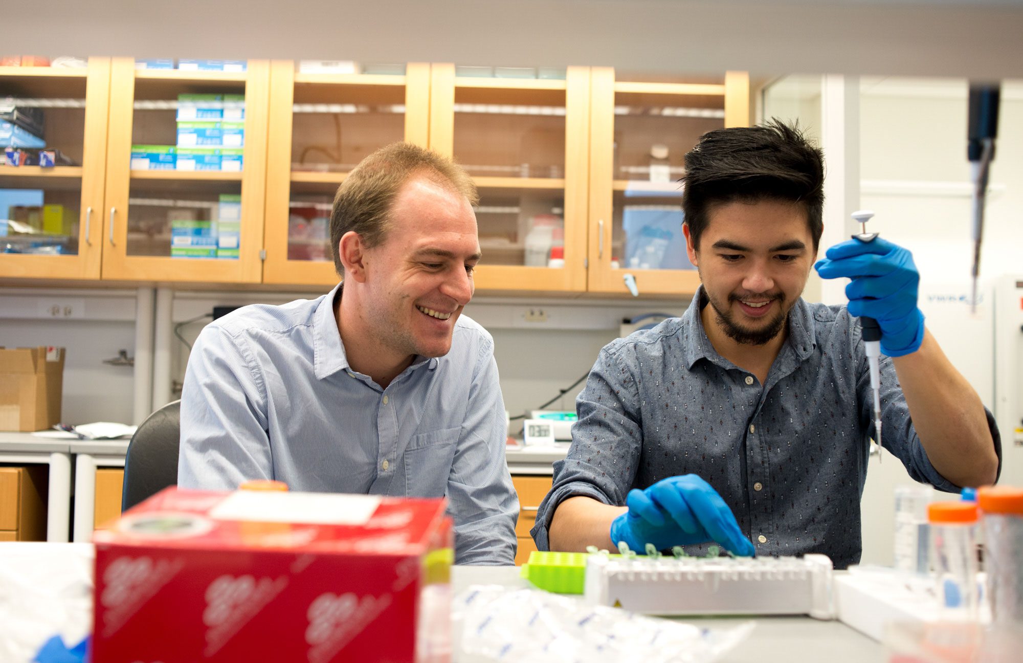 Two researchers work together among lab equipment