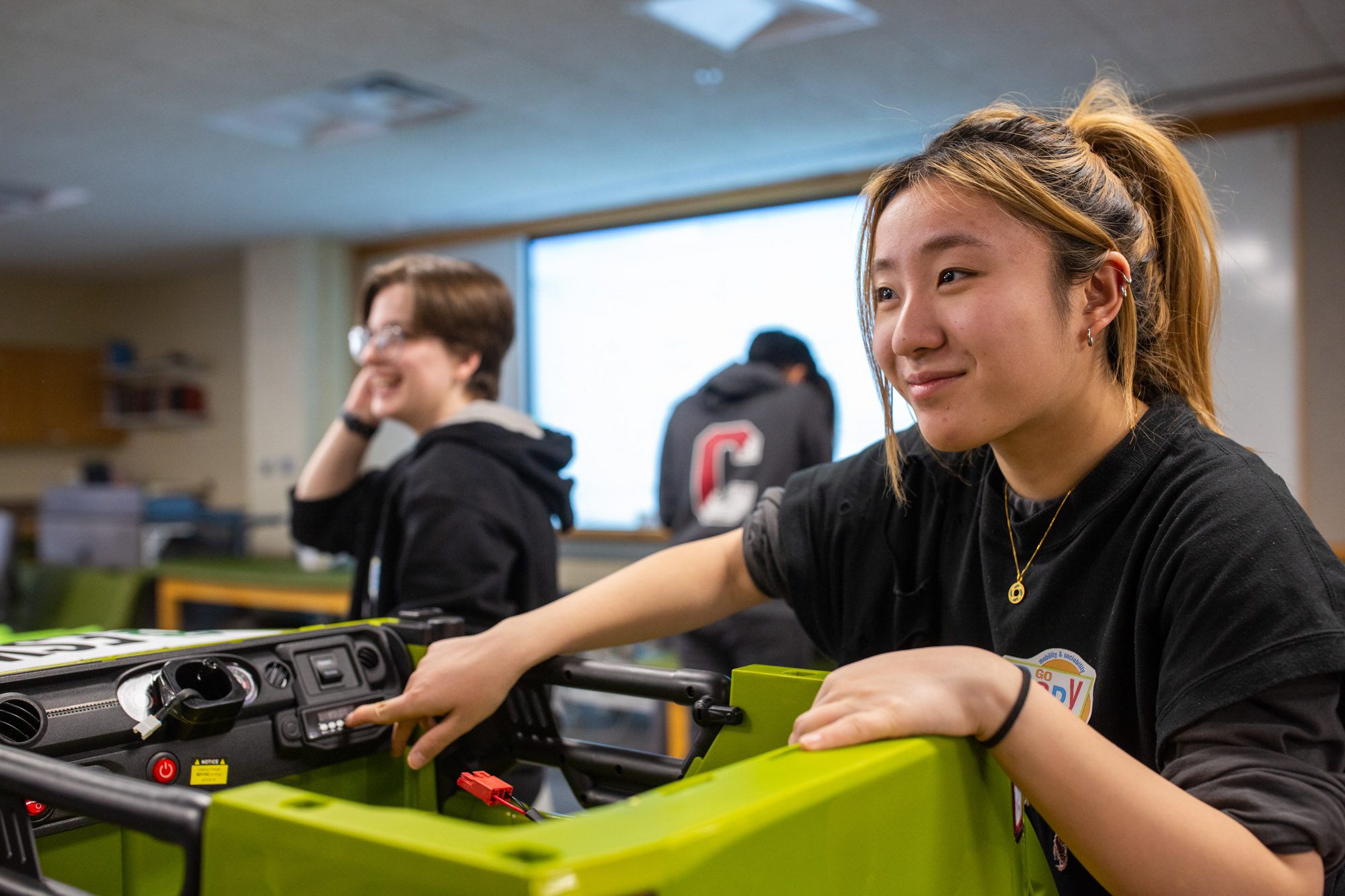 Two students smile while working with equipment