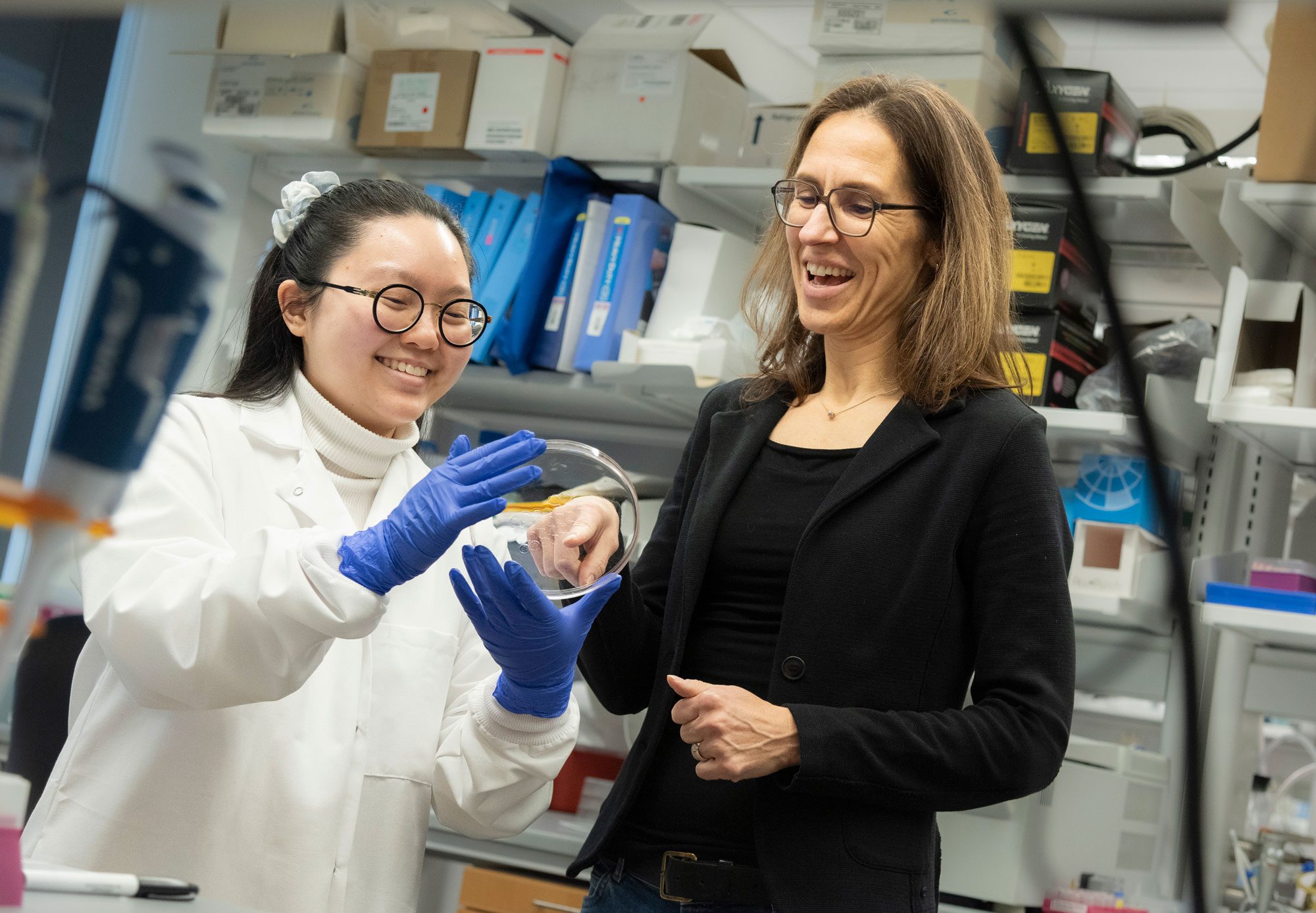 Claudia Fischbach smiles with student researcher as they look at equipment