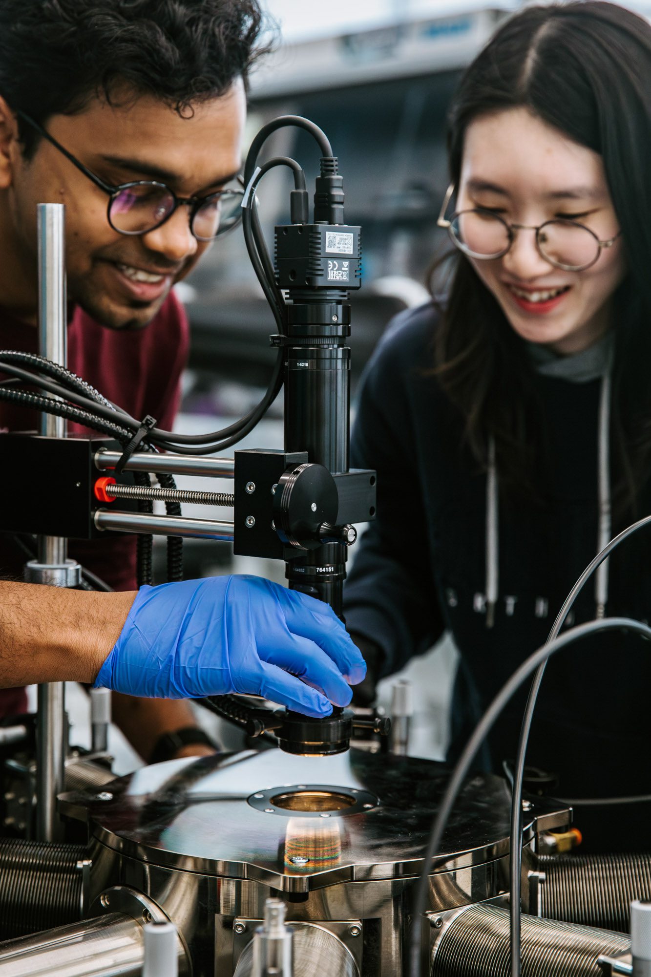 Two smiling student work together at metallic device