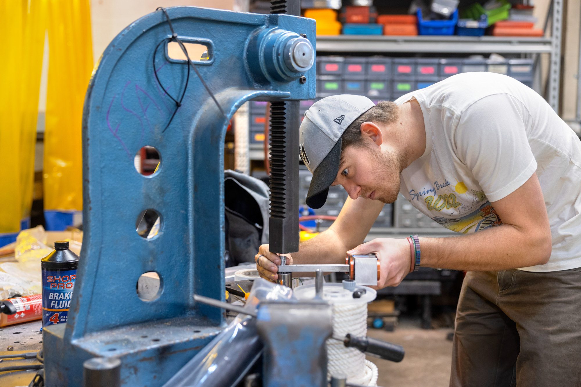 Student leans over while working at metal device