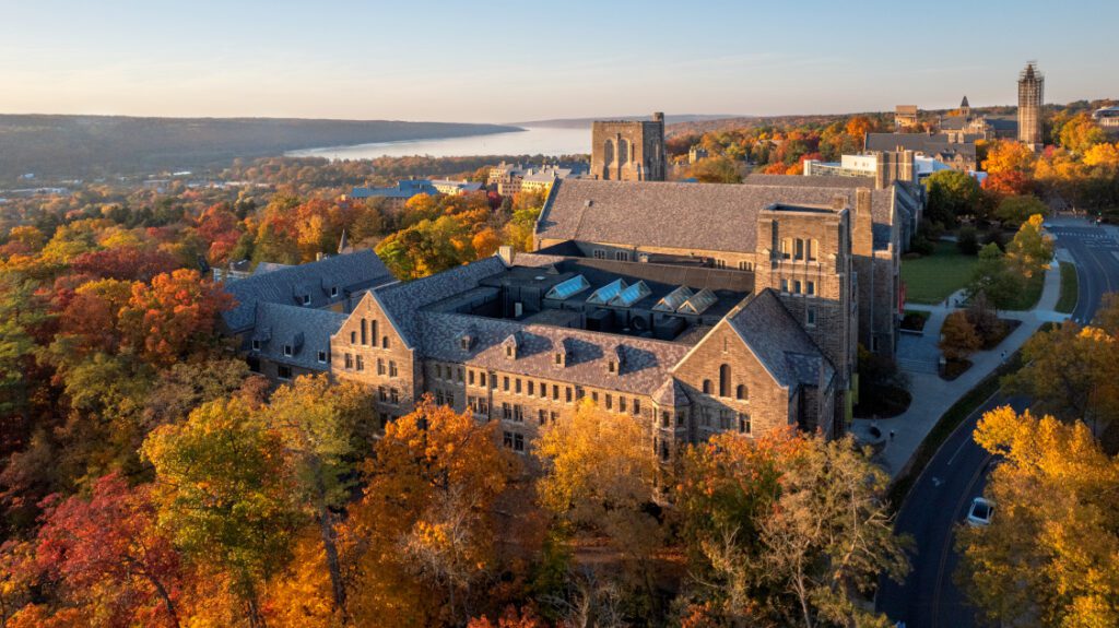 Aerial view of stone buildings, fall trees, and lake in background