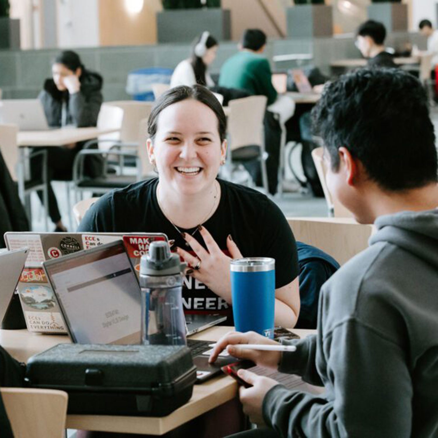 Students laugh together at table with laptops in Duffield Hall
