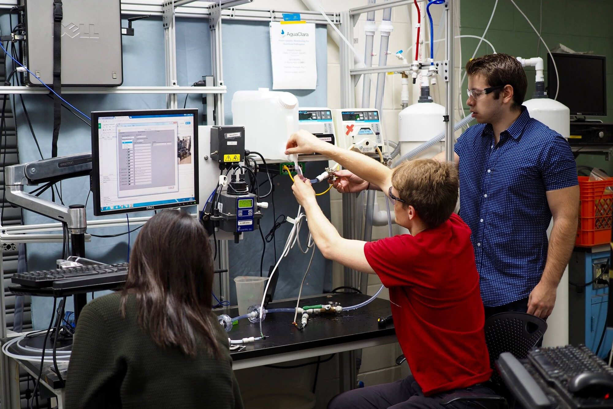 Three students work together on a water quality monitoring system