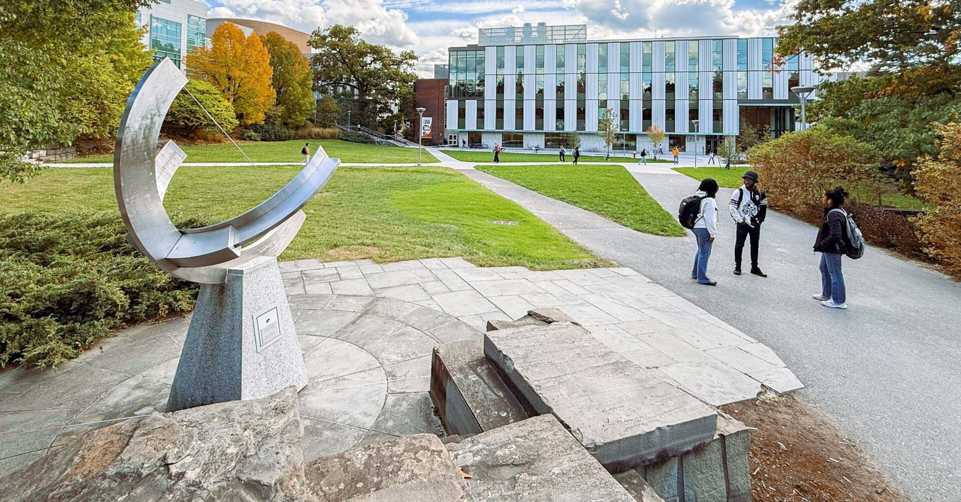 Students stop to talk by the Sundial on the Engineering Quad in front of Tang Hall