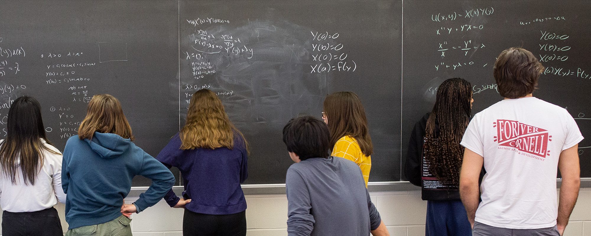 Students gather at a chalk board during a peer education workshop