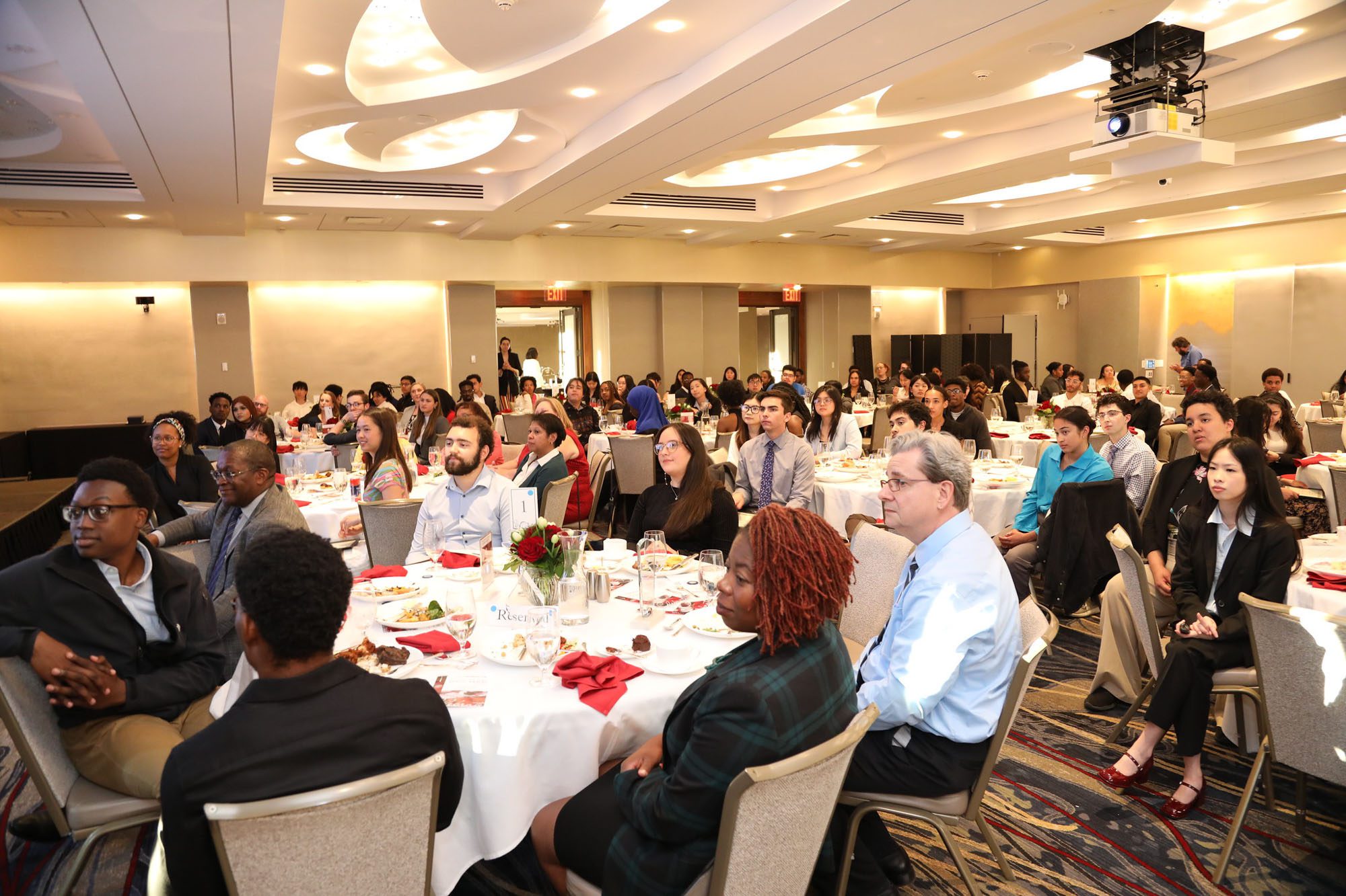 Many people sit together around banquet tables