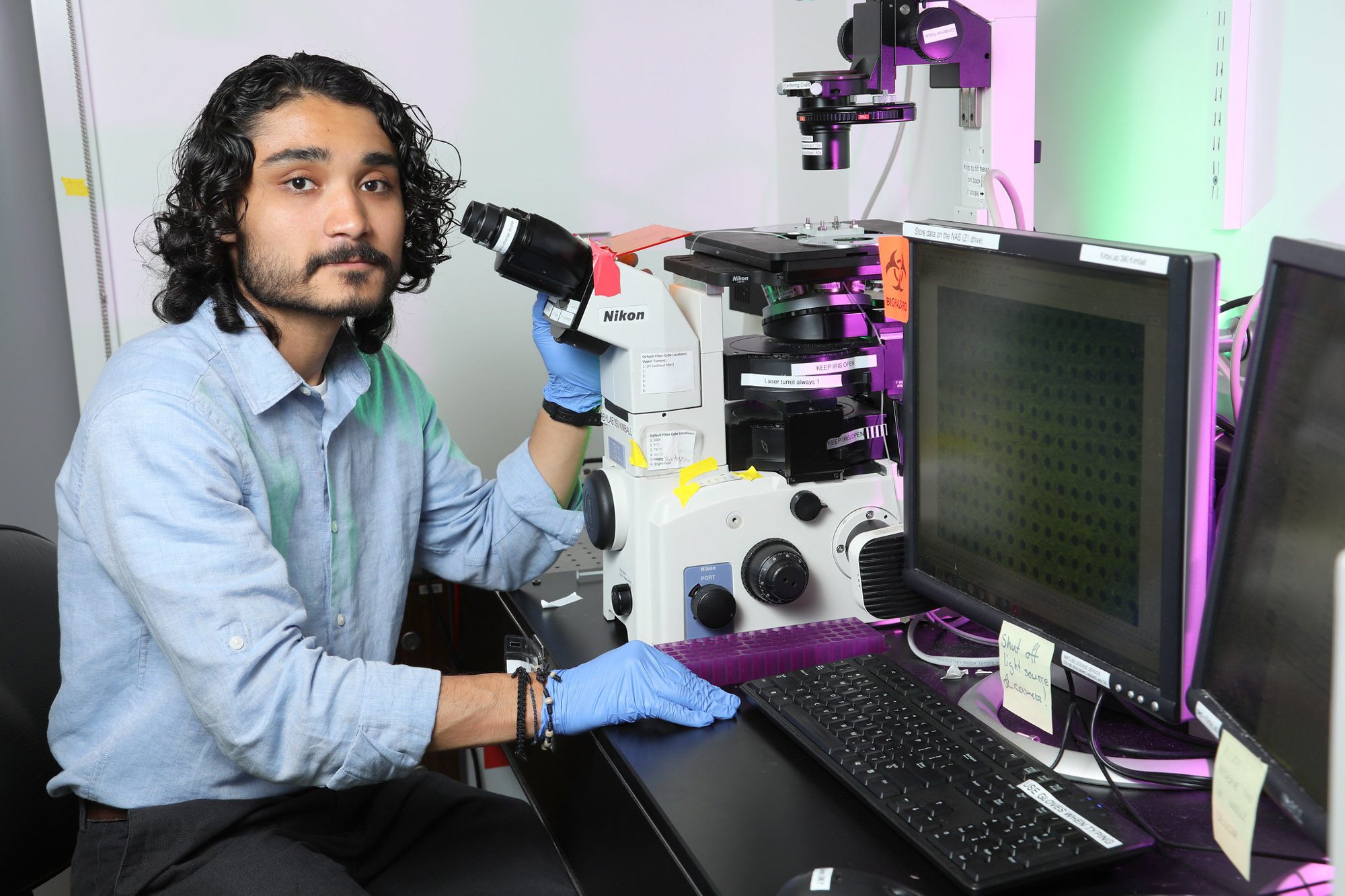 A student sits at a microscope