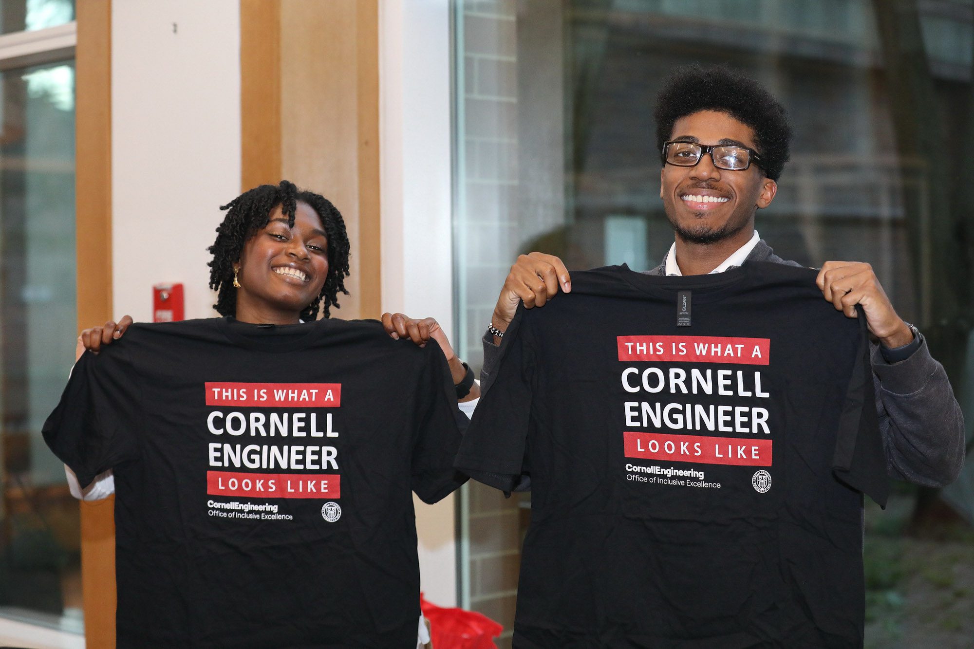 Two students hold up t-shirts that say 