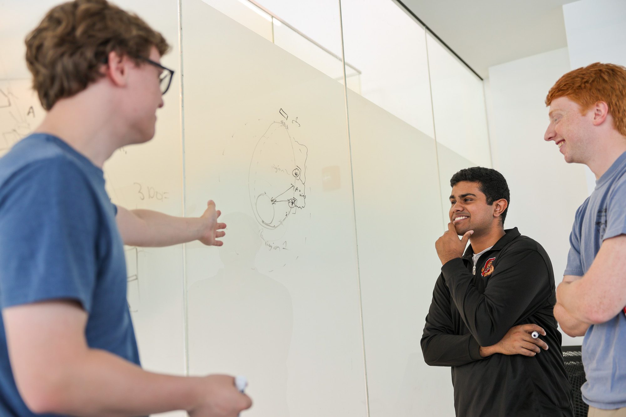 3 students working together in front of a white board