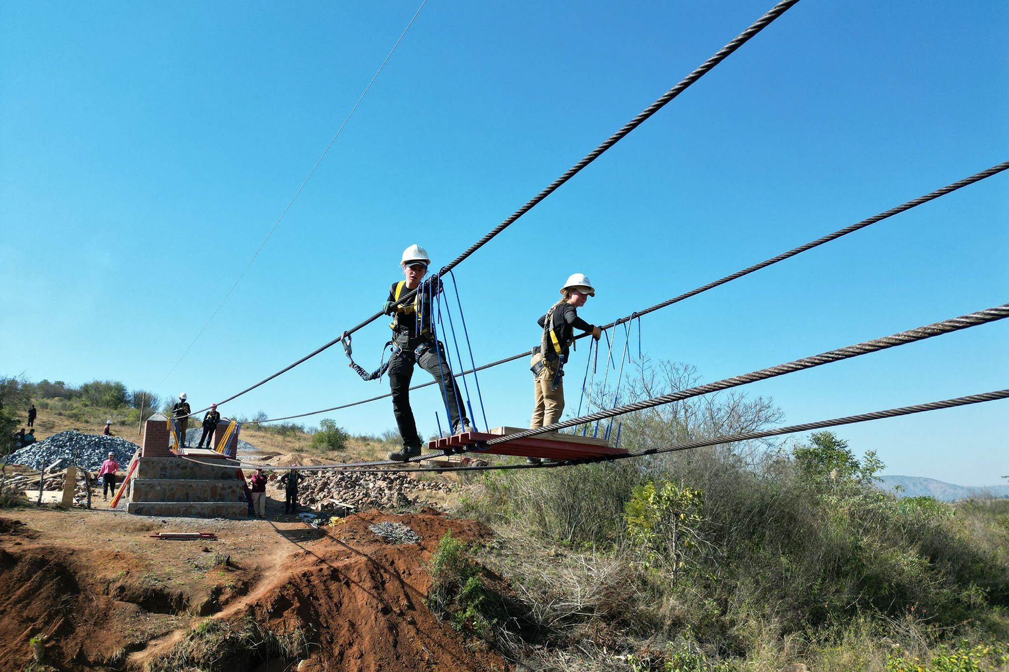 Students travel across cables for a bridge project in Eswatini